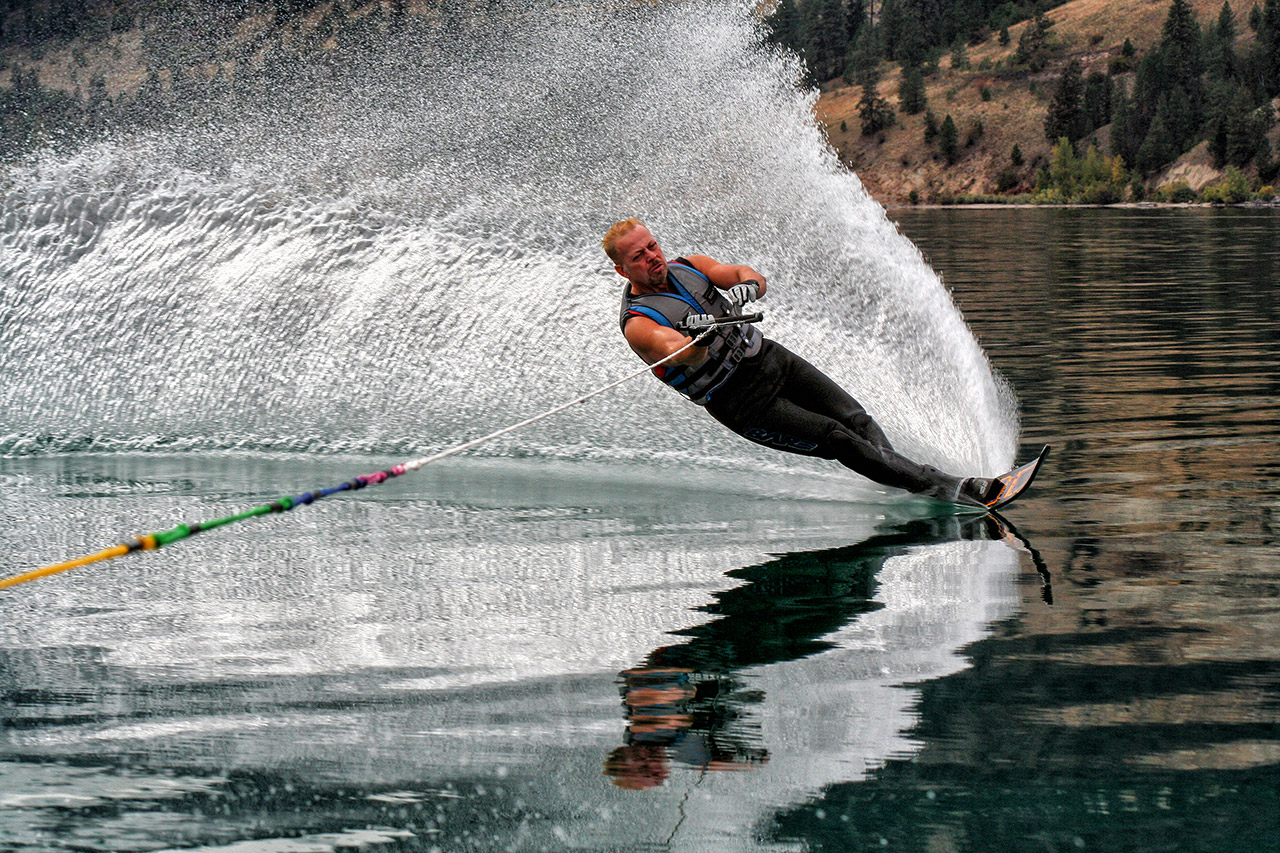 Male water skier carves turn on blue green lake waters