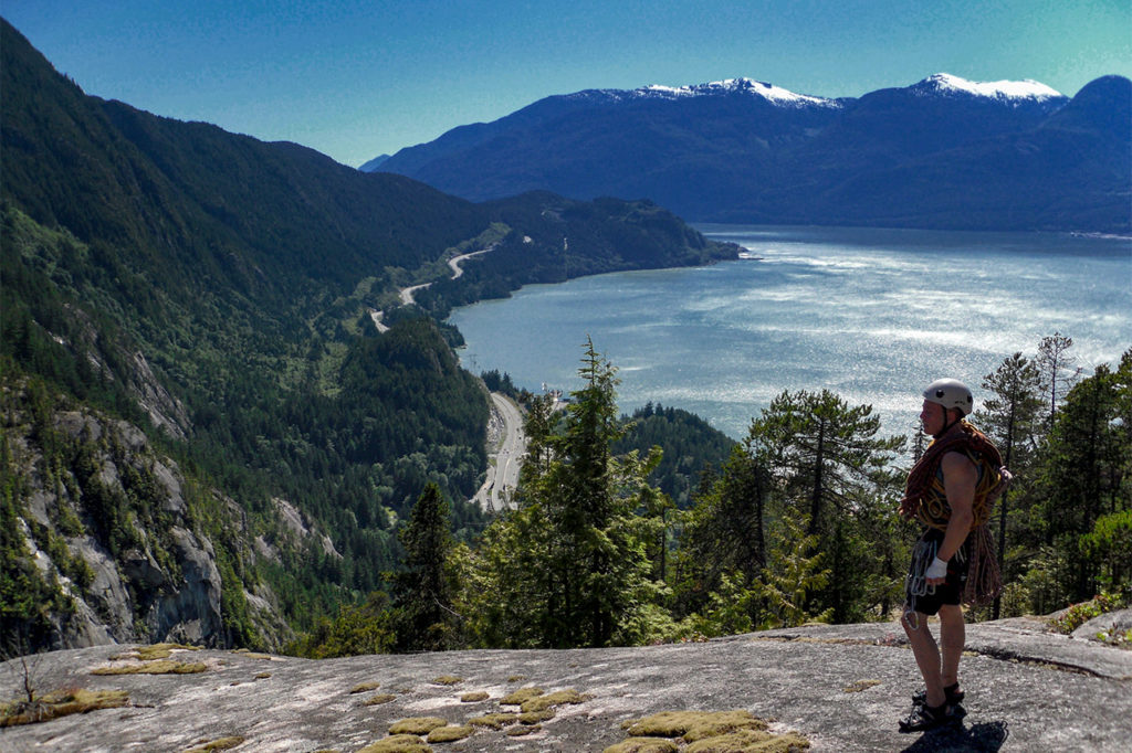 Climber standing on top the 2000 foot granite escarpment of the Stawamus Chief