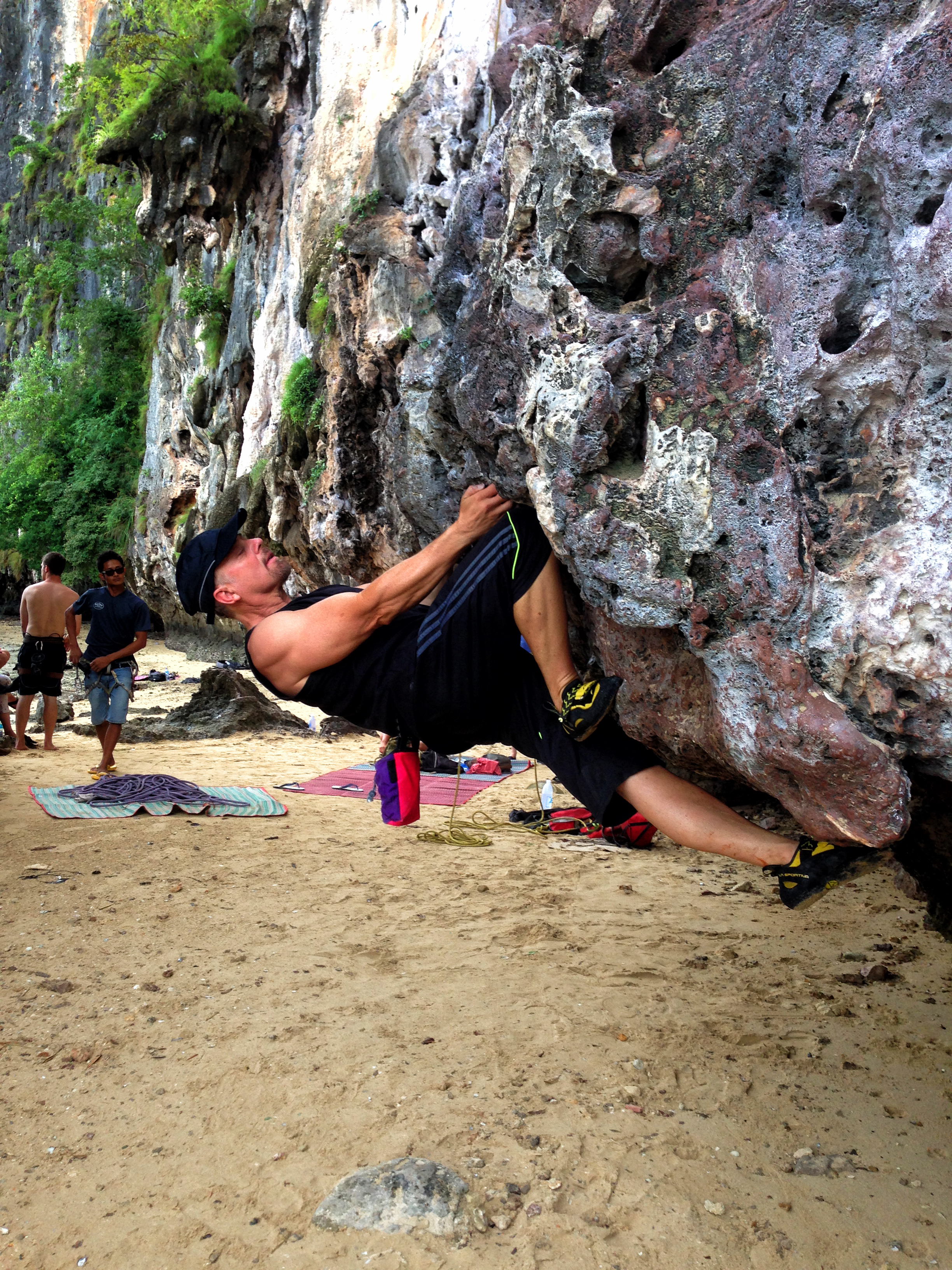 Rock climber navigates severe overhang just of the beach in Tonsai Thailand